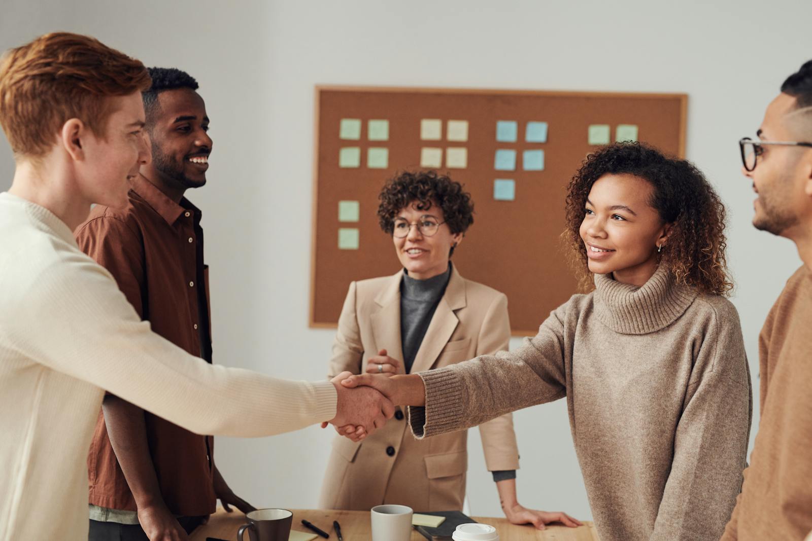 A diverse group of colleagues shaking hands during a productive office meeting.